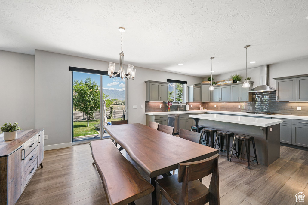 Dining space with wood finished floors, a chandelier, a textured ceiling, recessed lighting, and baseboards