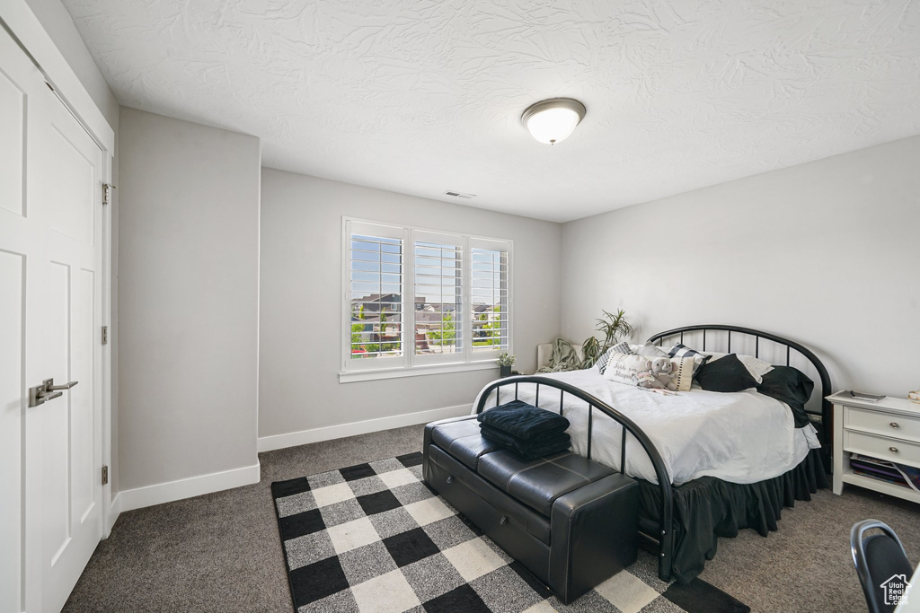 Bedroom with baseboards, a textured ceiling, and carpet