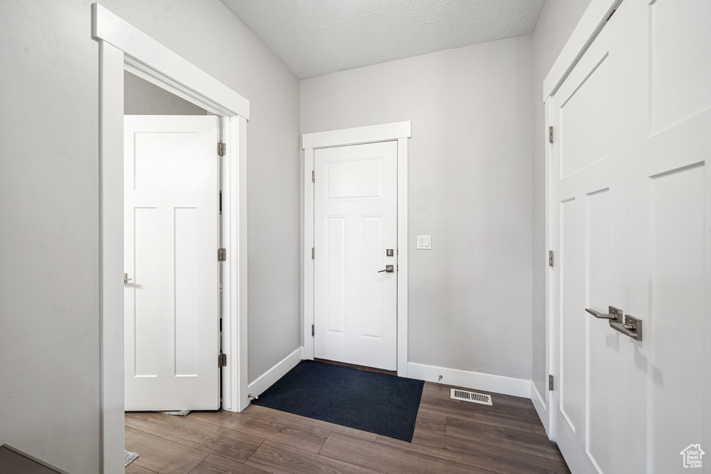 Foyer featuring dark wood-style flooring and baseboards