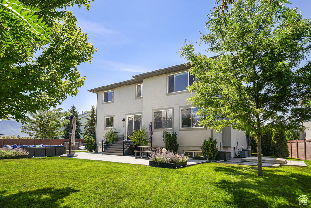 Back of house featuring stucco siding, central AC unit, and a patio