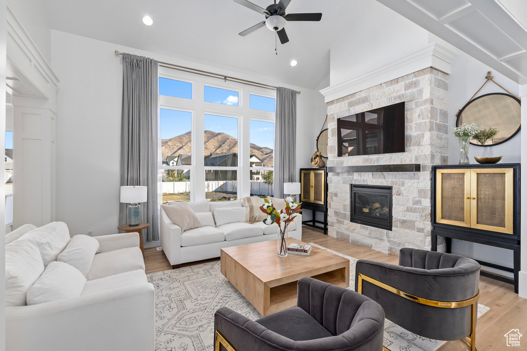 Living room featuring wood finished floors, a ceiling fan, a fireplace, recessed lighting, and lofted ceiling