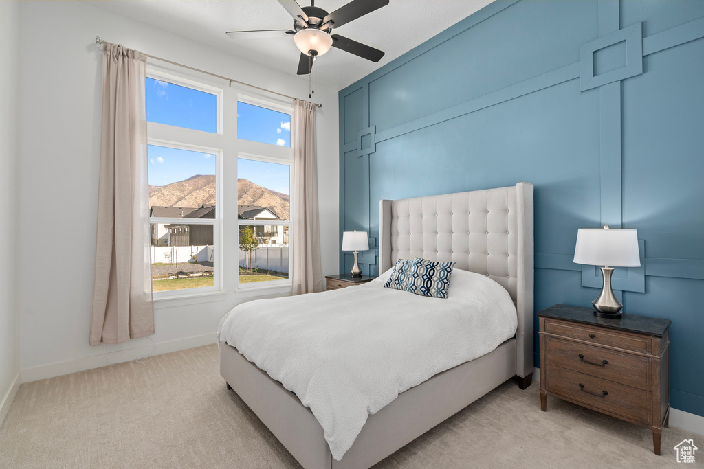 Bedroom featuring light carpet, baseboards, a ceiling fan, and a mountain view