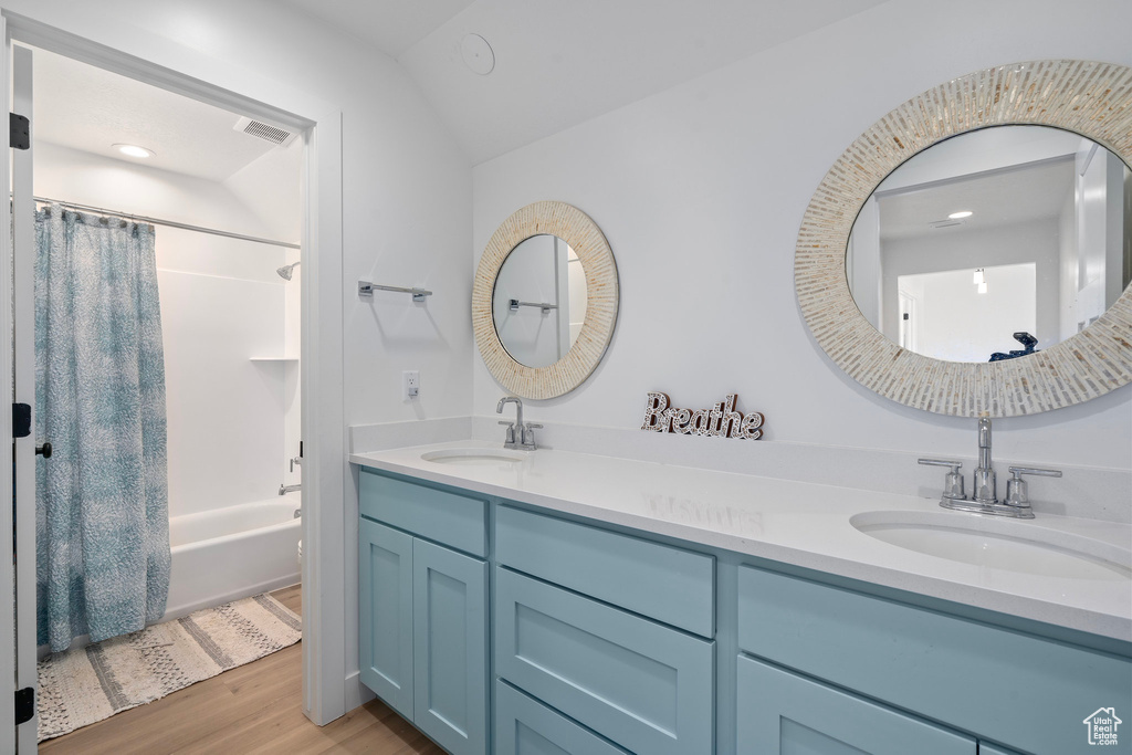 Full bath featuring double vanity, wood finished floors, shower / bath combo, and recessed lighting