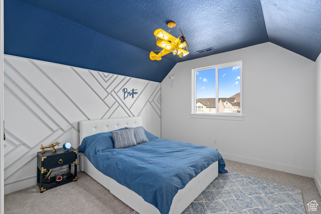 Bedroom featuring carpet flooring, vaulted ceiling, baseboards, and a textured ceiling