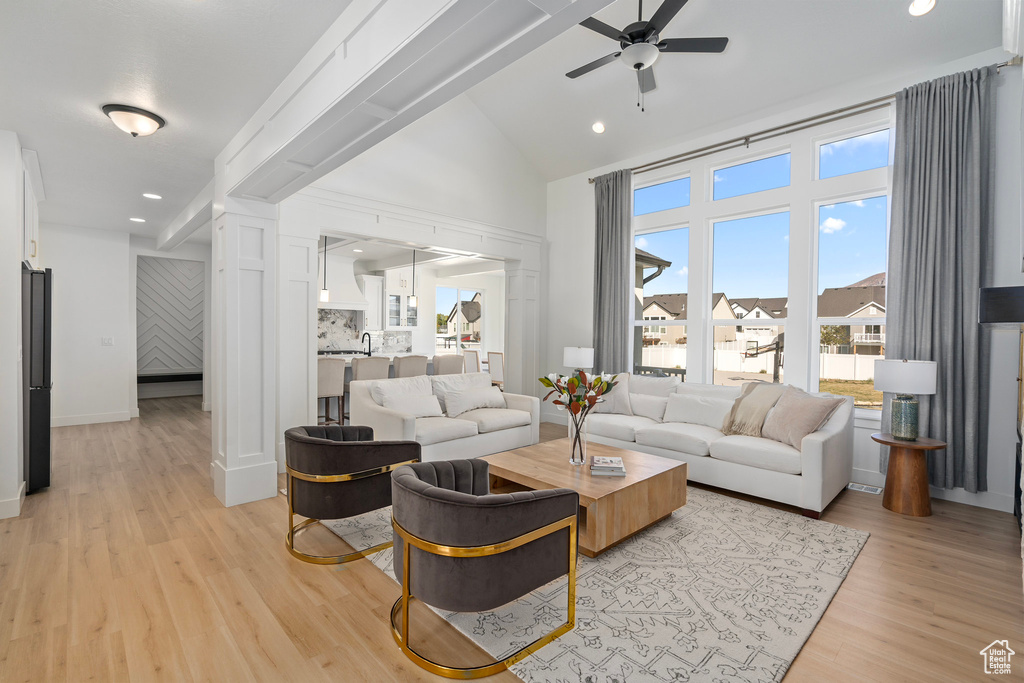 Living area with ceiling fan, light wood-style floors, high vaulted ceiling, recessed lighting, and baseboards