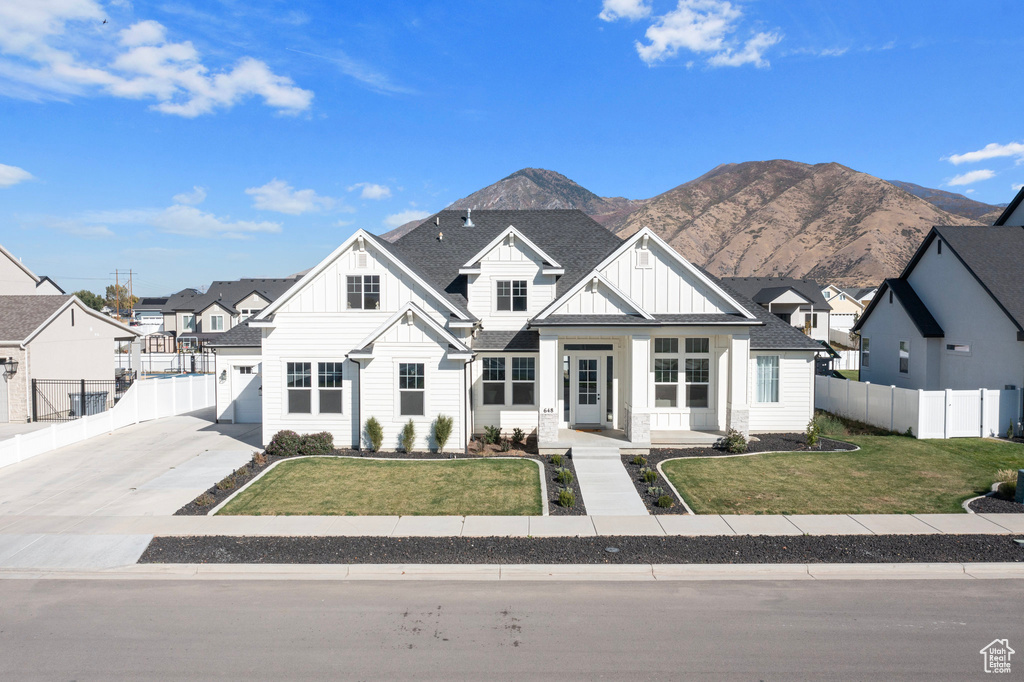 Modern farmhouse style home featuring board and batten siding, a mountain view, covered porch, roof with shingles, and driveway