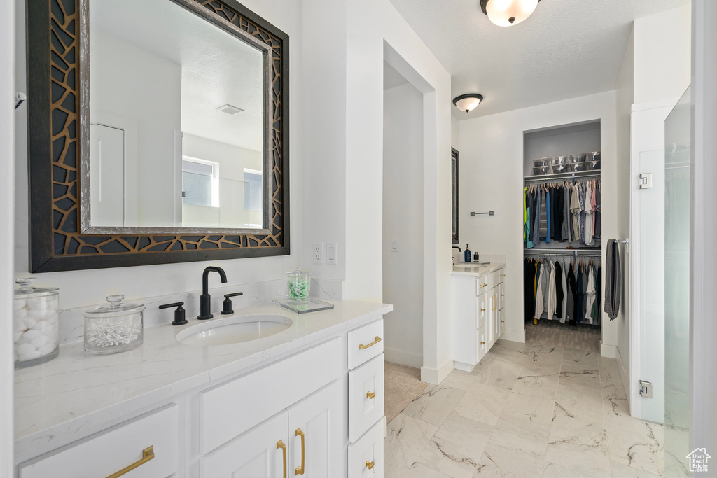 Bathroom featuring baseboards, vanity, marble finish flooring, and a walk in closet