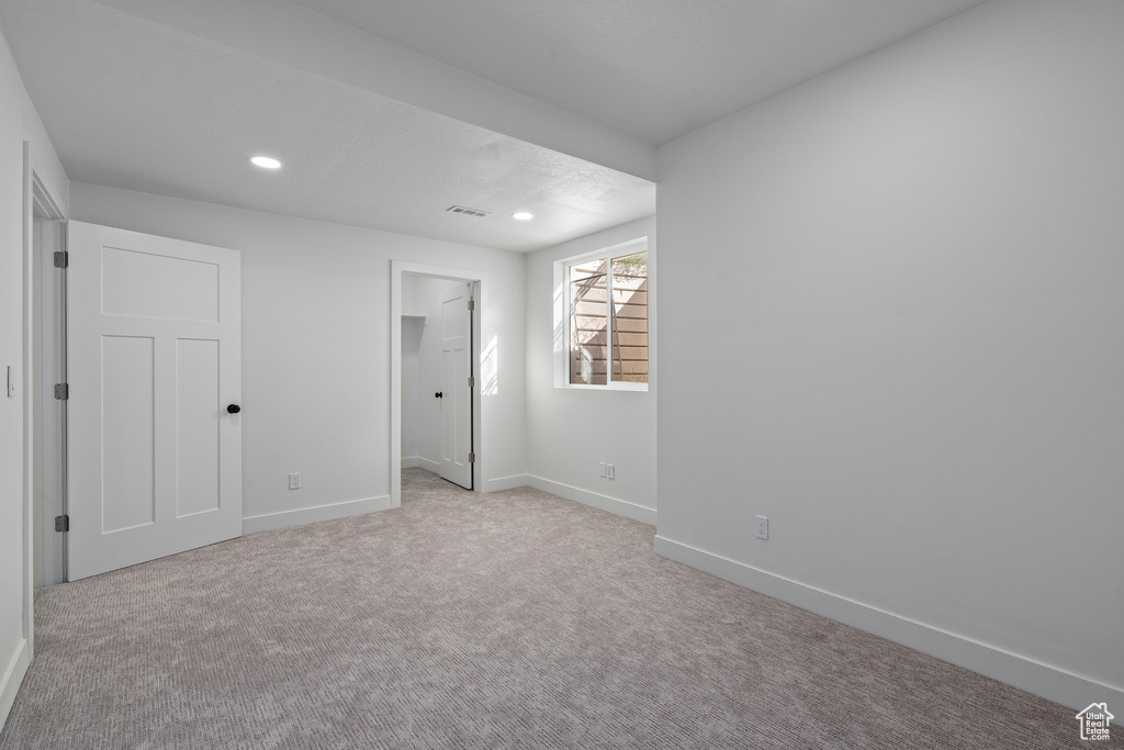 Unfurnished bedroom featuring baseboards, carpet, recessed lighting, and a walk in closet
