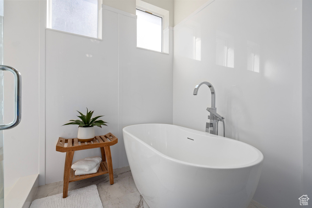 Full bath with marble look tile flooring and a freestanding bath
