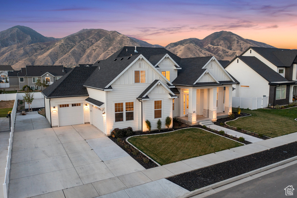 Modern inspired farmhouse with board and batten siding, driveway, a mountain view, an attached garage, and roof with shingles