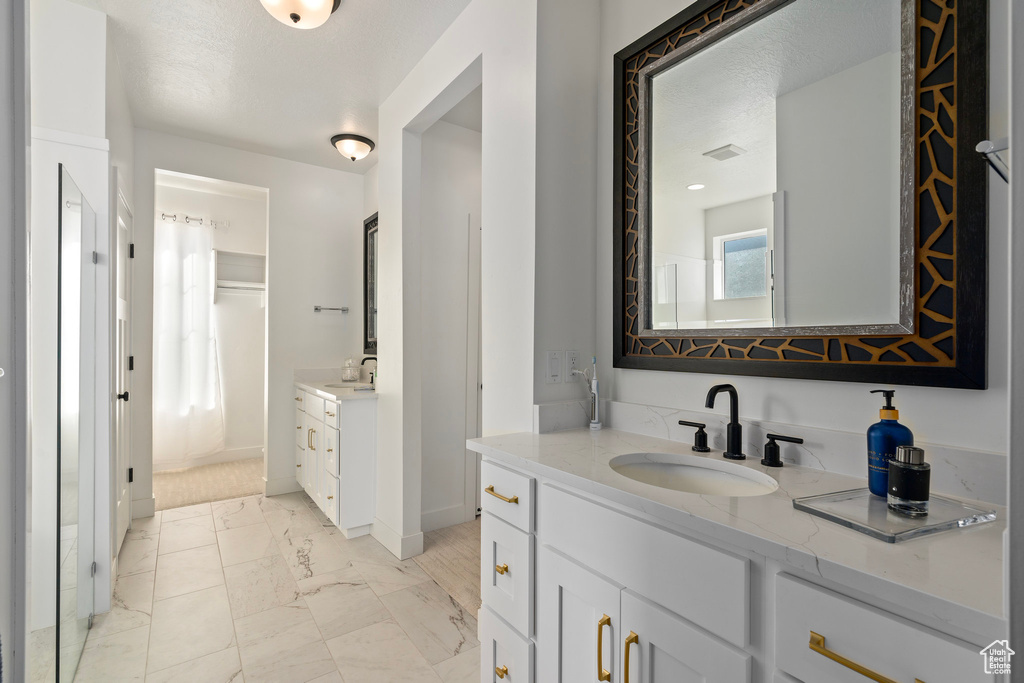 Bathroom featuring marble look tiles, baseboards, and two vanities