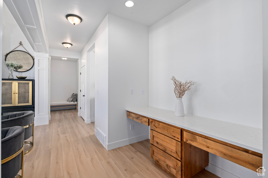 Unfurnished office featuring built in desk, light wood-style flooring, and baseboards