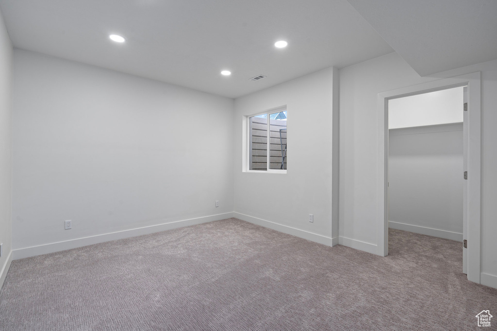 Unfurnished bedroom featuring a spacious closet, carpet floors, baseboards, and recessed lighting