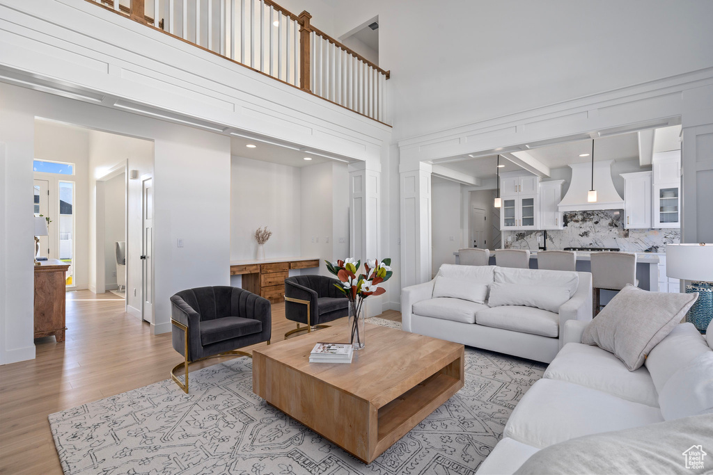 Living room with light wood-style floors, a high ceiling, and baseboards