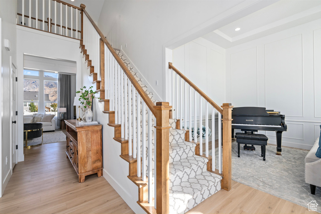 Stairway with wood finished floors, a decorative wall, and a high ceiling