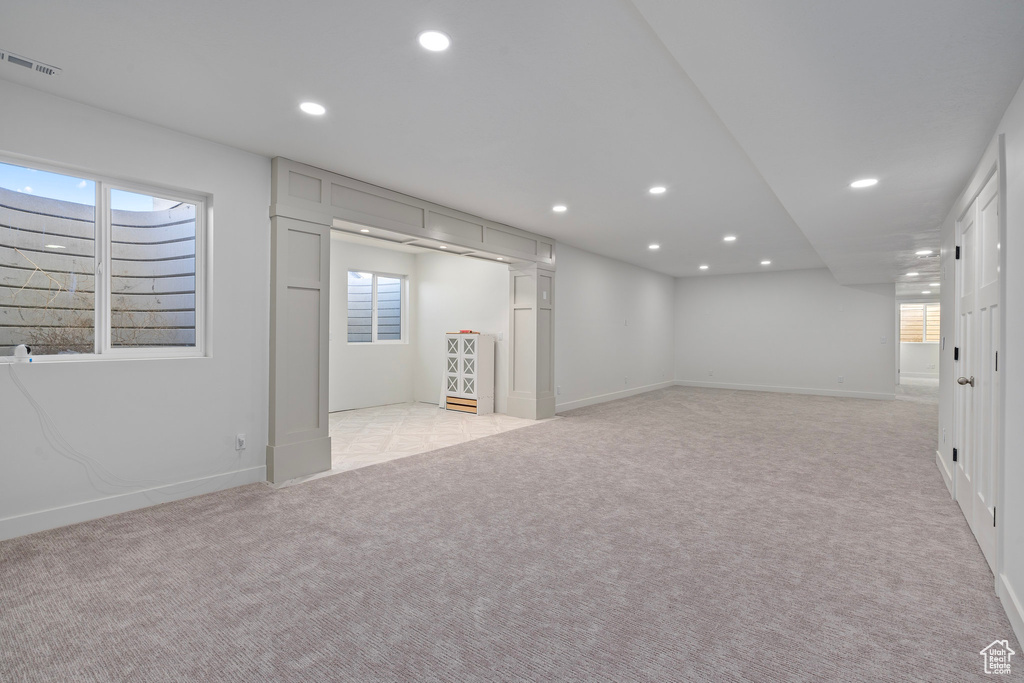 Below grade area with light colored carpet, recessed lighting, plenty of natural light, and baseboards