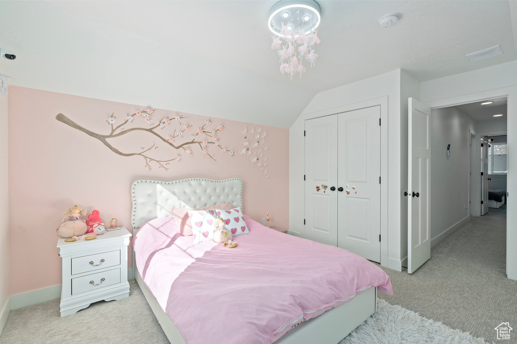 Bedroom with light colored carpet, a closet, baseboards, and lofted ceiling