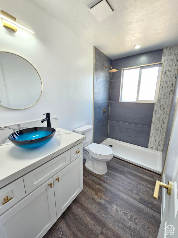 Full bathroom with vanity, a shower stall, toilet, wood finished floors, and a textured ceiling