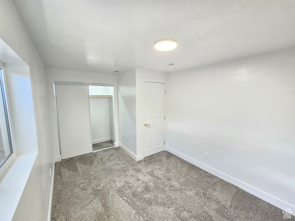 Unfurnished bedroom featuring carpet, baseboards, and a closet