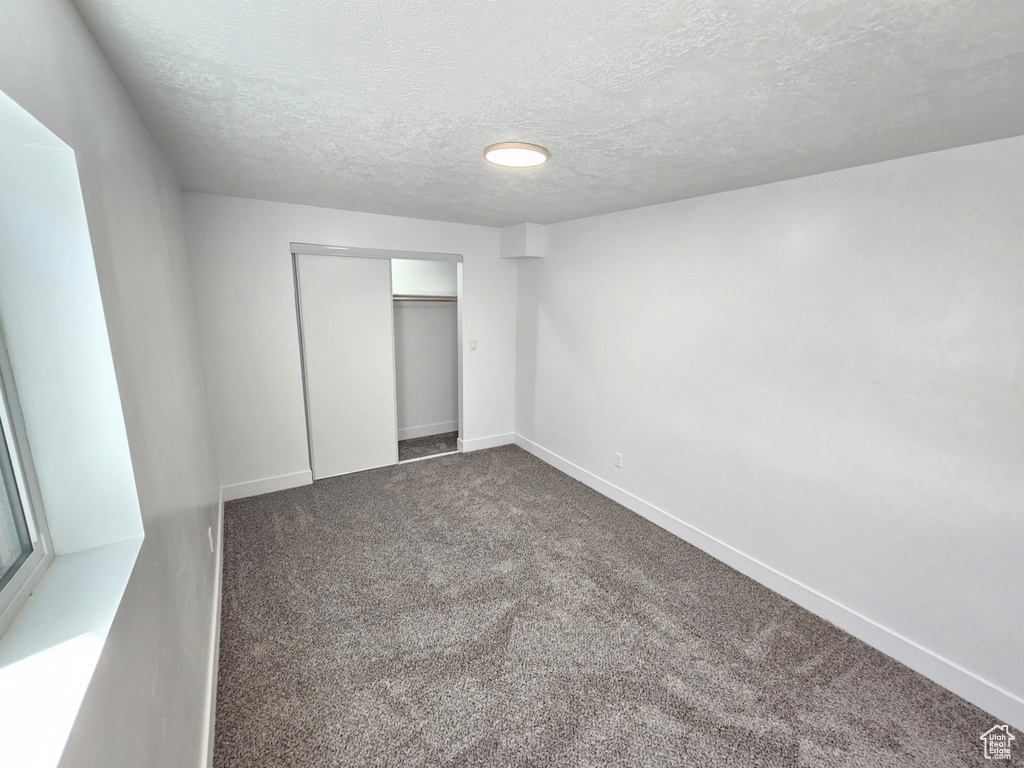 Unfurnished bedroom with baseboards, carpet floors, a closet, and a textured ceiling