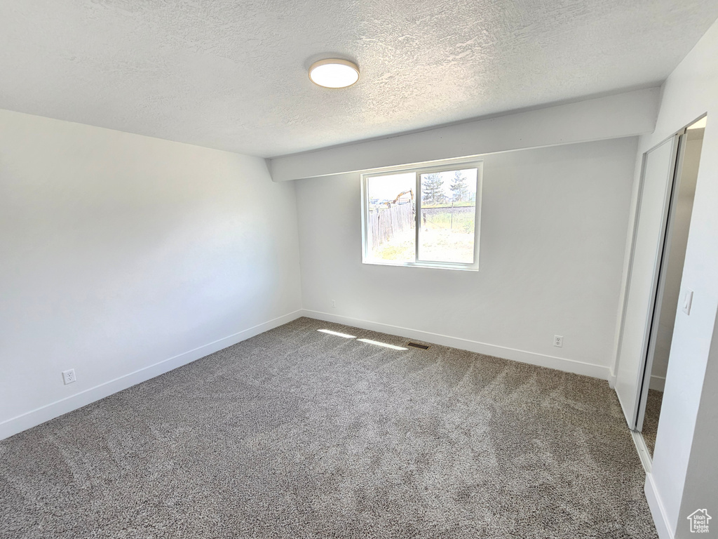Unfurnished bedroom featuring carpet floors, baseboards, and a textured ceiling