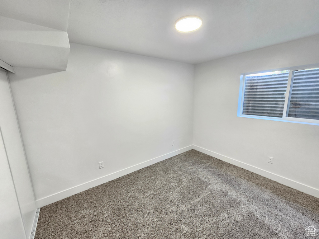 Spare room featuring dark colored carpet and baseboards