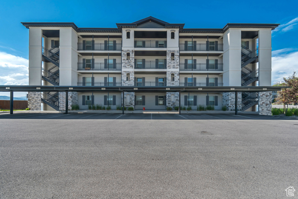 View of apartment building / complex featuring stairs and covered parking