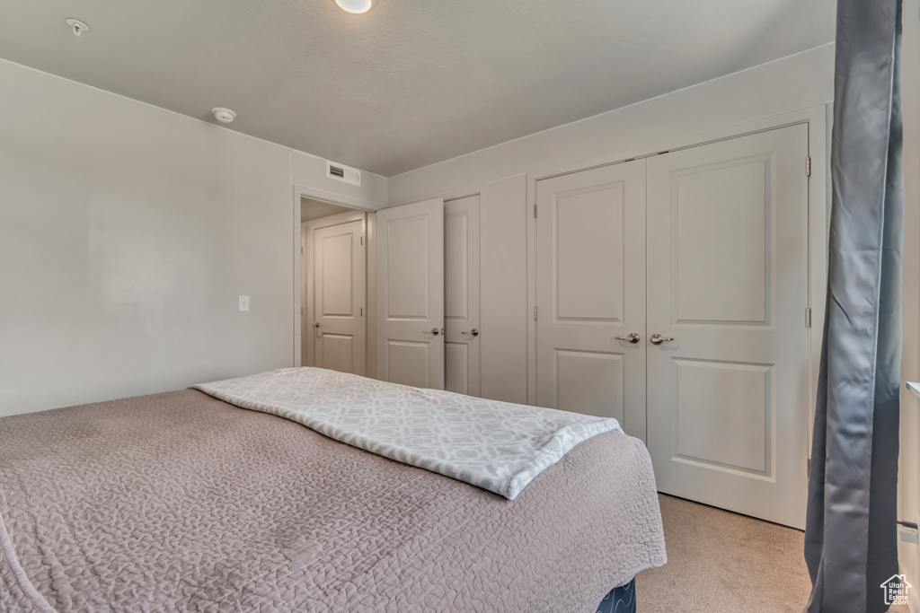 Bedroom featuring light carpet and two closets