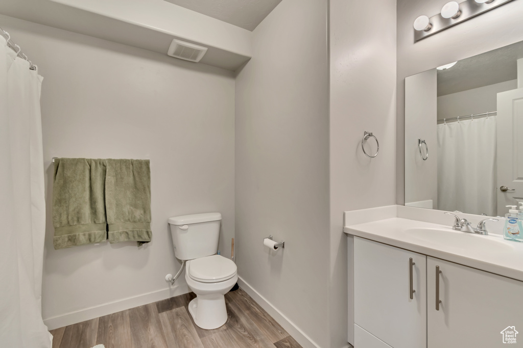 Bathroom with toilet, wood finished floors, baseboards, and vanity