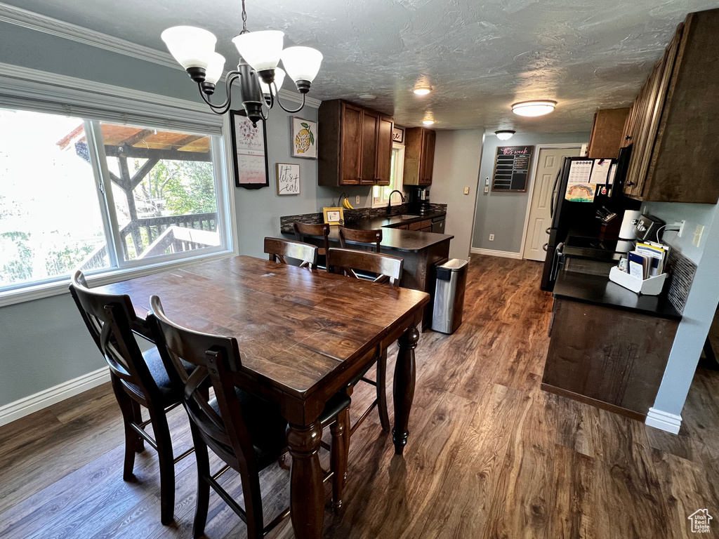 Dining area featuring baseboards, a chandelier, dark wood-style flooring, and ornamental molding