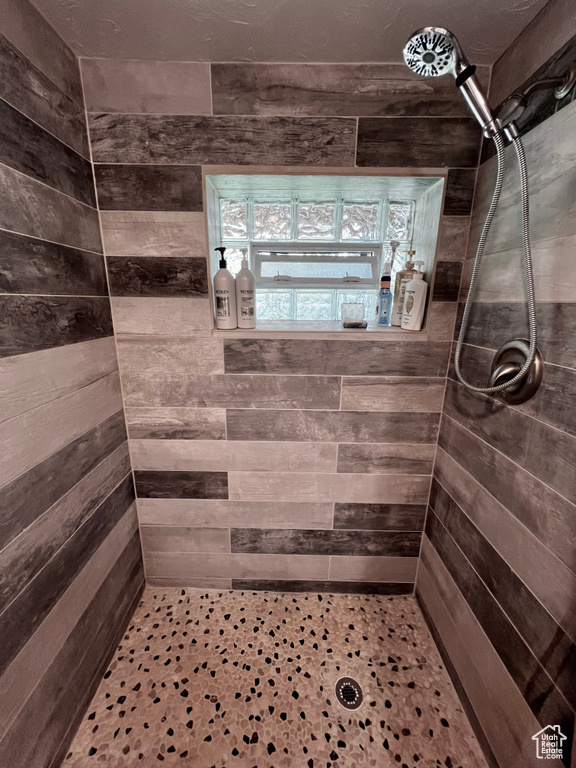 Full bathroom with tiled shower and wood walls