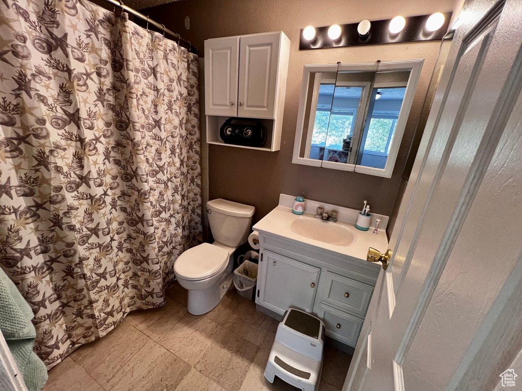 Bathroom with vanity, toilet, and curtained shower