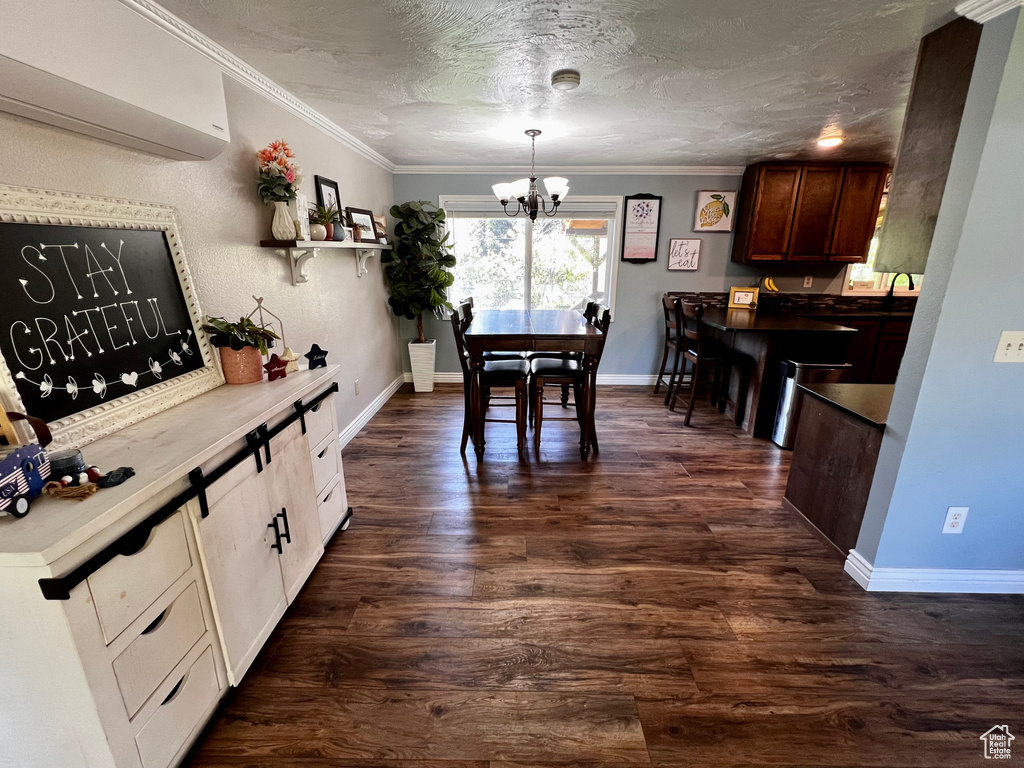 Dining room featuring a wall unit AC, a chandelier, dark wood-style floors, ornamental molding, and baseboards