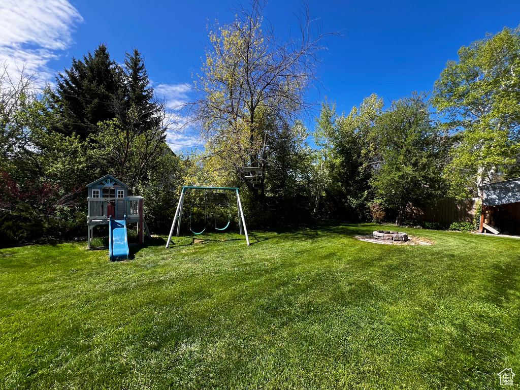 View of yard featuring a playground and a fire pit