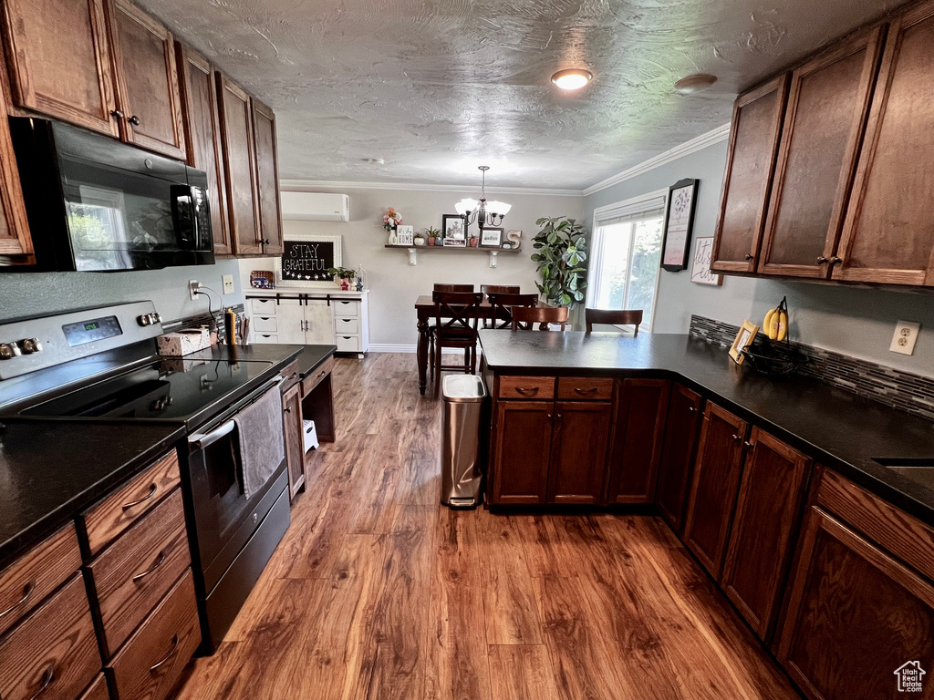 Kitchen featuring black microwave, stainless steel range with electric cooktop, dark countertops, dark wood-style flooring, and ornamental molding