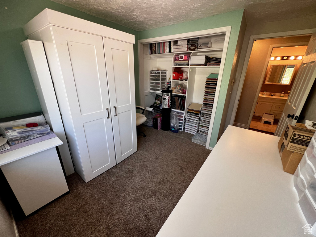 Bedroom featuring a closet, dark colored carpet, and a textured ceiling