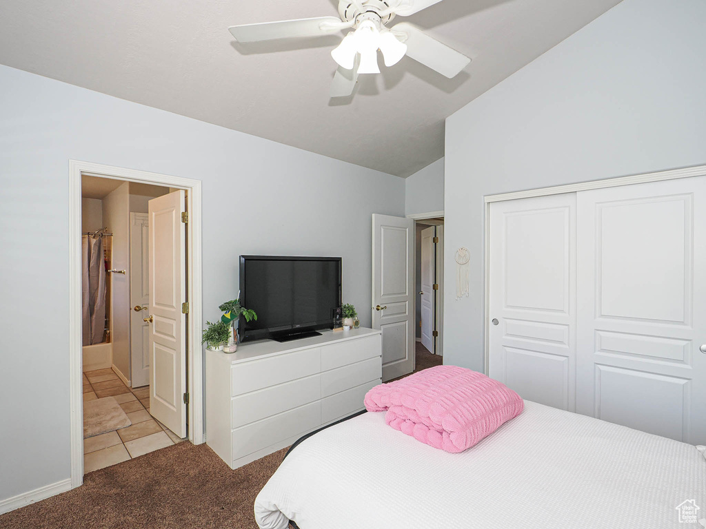 Carpeted bedroom featuring vaulted ceiling, a closet, connected bathroom, and a ceiling fan