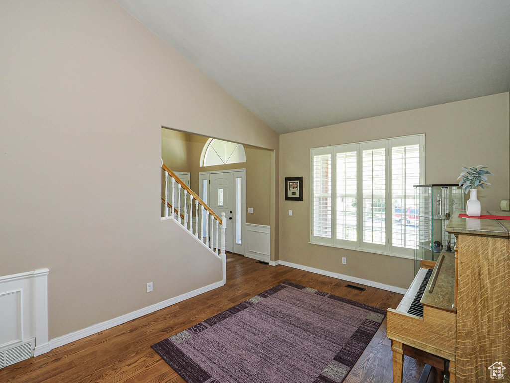 Foyer entrance featuring wood finished floors, stairs, baseboards, and high vaulted ceiling