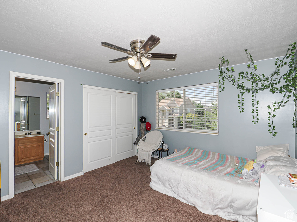 Bedroom with carpet flooring, a closet, baseboards, connected bathroom, and a ceiling fan