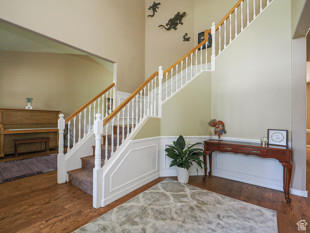 Stairway featuring wood finished floors and a towering ceiling
