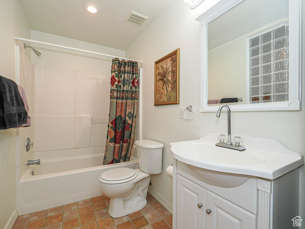 Bathroom featuring vanity, baseboards, shower / bath combination with curtain, toilet, and stone finish floors