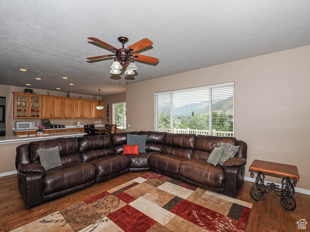 Living area with wood finished floors, baseboards, ceiling fan, and recessed lighting