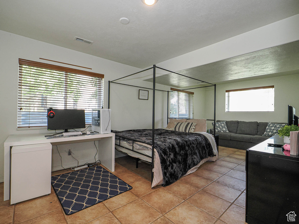 Bedroom featuring light tile patterned floors and an office area