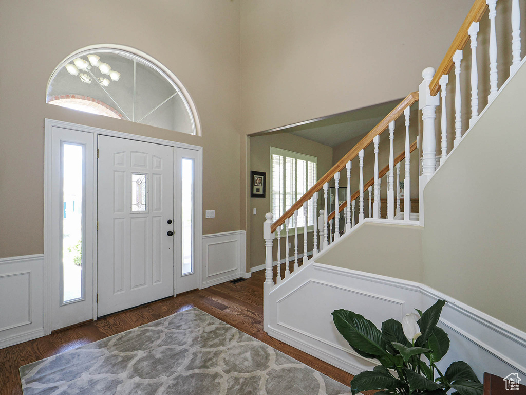 Foyer featuring wainscoting, stairs, wood finished floors, and a decorative wall