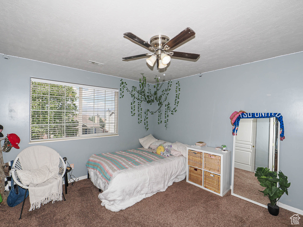 Carpeted bedroom featuring baseboards, a ceiling fan, and a textured ceiling