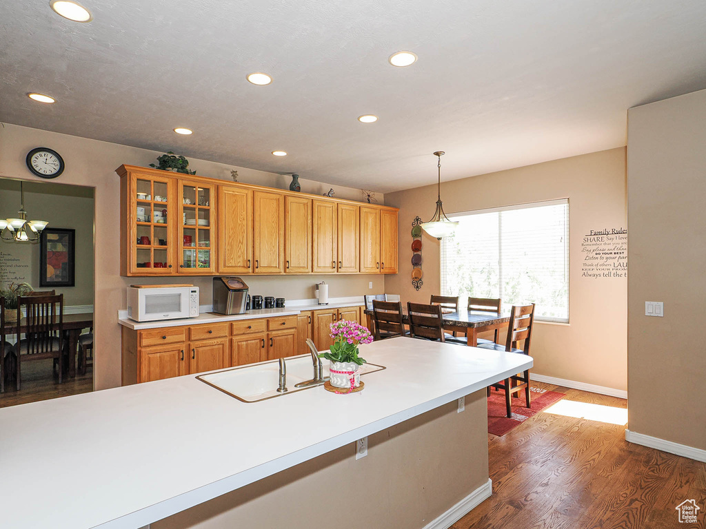 Kitchen with white microwave, a sink, dark wood-style floors, baseboards, and recessed lighting