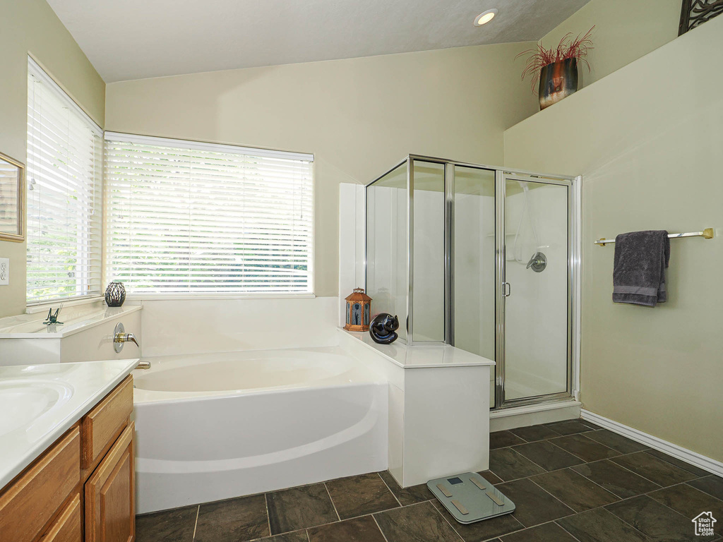 Bathroom with a garden tub, vanity, a shower stall, and lofted ceiling
