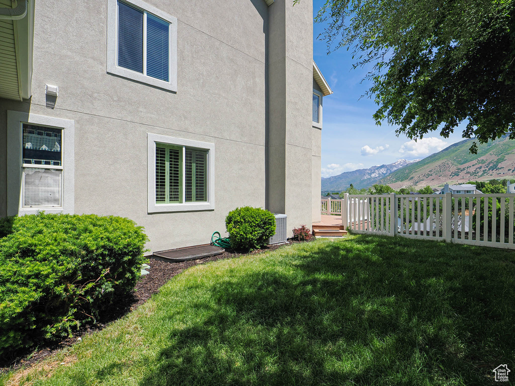 View of property exterior with stucco siding, a mountain view, and central AC