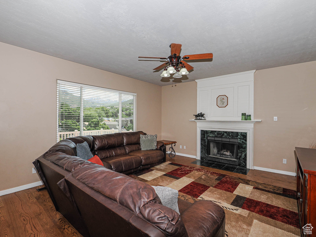 Living room featuring wood finished floors, baseboards, a ceiling fan, and a premium fireplace