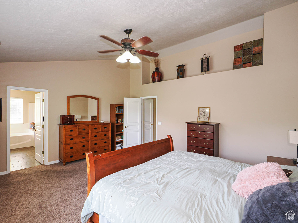 Carpeted bedroom featuring vaulted ceiling, ceiling fan, baseboards, and ensuite bathroom
